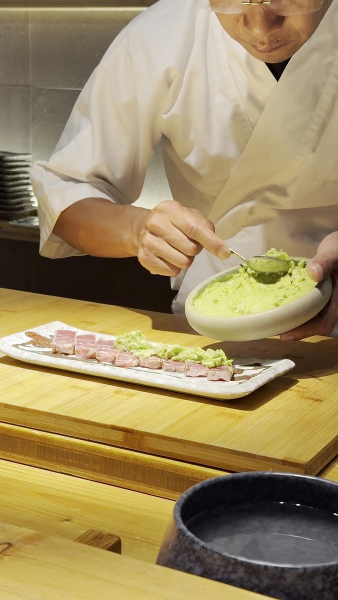 Un cocinero rallando wasabi junto a láminas de pescado